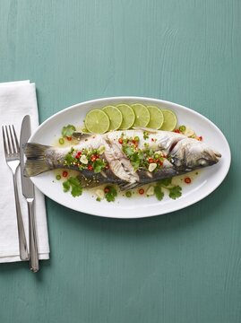 Whole sea bass with lime garlic and chili on a white platter