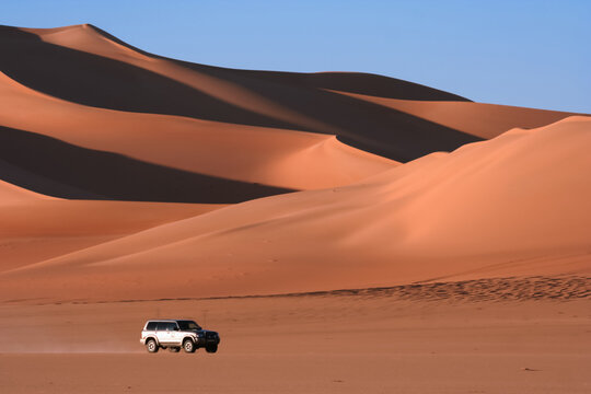 Libyan desert dunes, blue sky, off-road vehicle