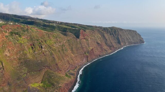 Atlantic coast of Madeira with extensive cliff walls, Portugal. Aerial footage of island coastline beneath coastal plateau
