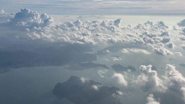Aerial view from above the clouds showing the tropical landscape and coastline of Langkawi, Malaysia, partially visible through dramatic clouds