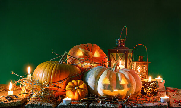 Halloween pumpkins with burning candles and vintage lanterns on wooden table