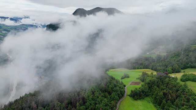 Dense low clouds hide mountain valley and green slopes in Dolomites, South Tyrol, Italy. Drone footage