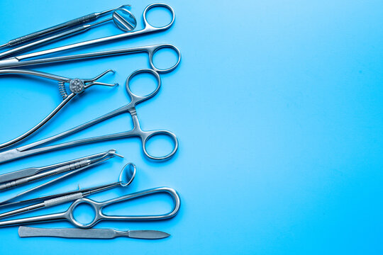 Set of stainless surgical instruments and tools - scalpels, scissors and others - on blue table, top view