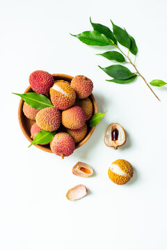 Exotic lychee fruit with green leaves in wooden bowl, top view. Healthy vegetarian meal