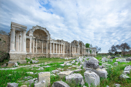 The Ancient City of Side. This photograph shows the remains of an ancient Nymphaeum (monumental fountain). In the background, there are columns, arches, and the tall, majestic stone fa&ccedil;ade of the anci