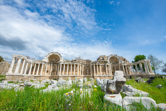 The Ancient City of Side. This photograph shows the remains of an ancient Nymphaeum (monumental fountain). In the background, there are columns, arches, and the tall, majestic stone fa&ccedil;ade of the anci