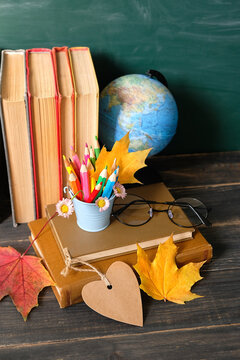 school supplies, globe, fallen maple leaves, eyeglass, empty greeting card and books on table close up. Education, 1 September, Knowledge Day, back to school, Teacher's day holiday concept.