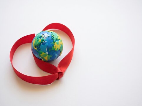 World aids day earth globe wrapped in heart shaped red ribbon isolated on white background