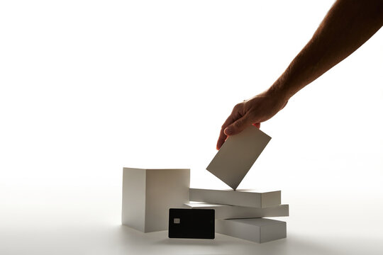 Hand Arranging White Geometric Podiums and Mockup Boxes with Black Credit Card on White Background