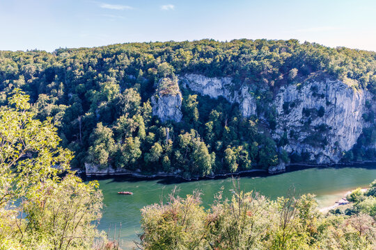 Aerial view of the Danube Gorge with steep limestone cliffs, dense forest and a tour boat on the green Danube River near Kelheim, Lower Bavaria, Germany, scenic nature landscape