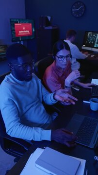 Vertical video of African American engineer and Caucasian young adult woman solving cyber attack at computers. Footage perfect for cybersecurity marketing and technology training projects