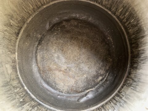 Inside view of an old used metal bucket with textured bottom and scratches.