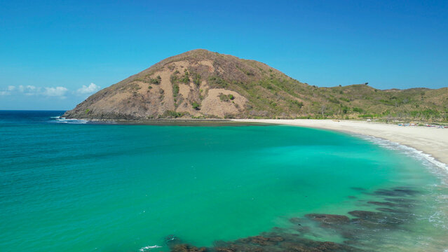 Aerial drone view of Mawun Beach Lombok Indonesia featuring turquoise horseshoe bay curved white sand shoreline and green hills