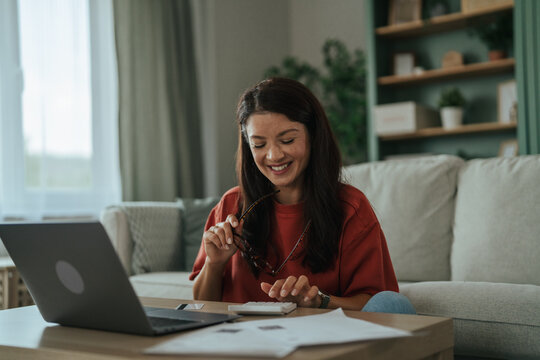 Woman managing personal finances at home using calculator