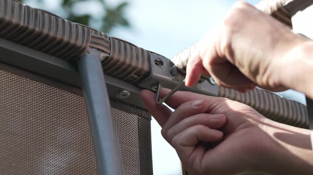 Hands tighten screws on outdoor screen frame