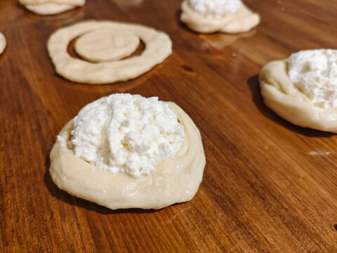 Unbaked Open-Faced Cottage Cheese Buns Arranged on a Wooden Table