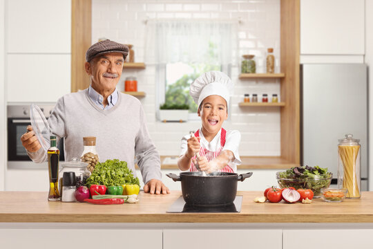 Happy little boy cooking with his grandpa in a kitchen