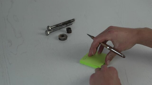 Hand writes on bright green sticky note