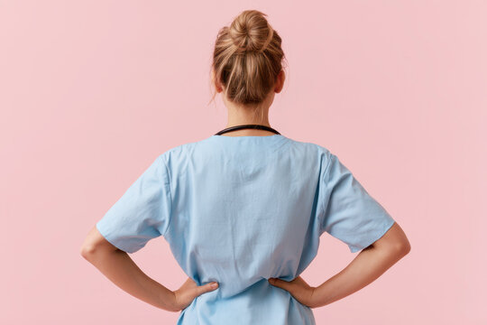 Healthcare worker standing with hands on hips, wearing blue scrubs and stethoscope, symbolizing medical profession and care