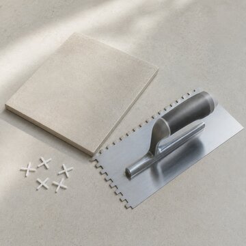 Tile installation tools with ceramic tile trowel and spacers on neutral surface