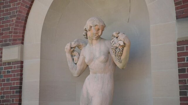 Close-up of a classical marble statue depicting a woman with grapes and a small animal at her side, displayed at the Hall of Springs in Saratoga Springs, New York.