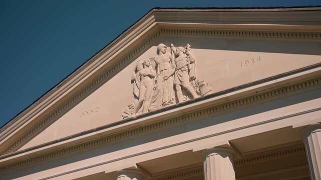 Detailed close-up of the neoclassical pediment atop the Hall of Springs in Saratoga Springs, New York, featuring sculpted figures and the date "ANNO 1934"
