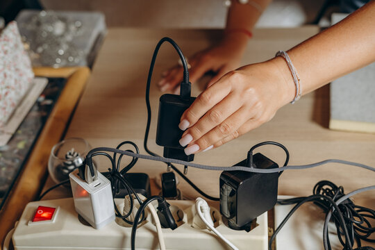 Cluttered Power Strip With Multiple Chargers, Adapters and Cables on Wooden Desk