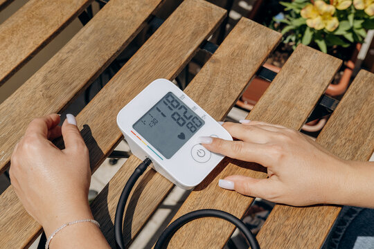 Woman Checking Blood Pressure With Digital Monitor At Home On Wooden Table, Health Check
