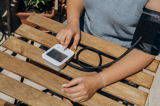 Woman Checking Blood Pressure With Digital Monitor At Home On Wooden Table, Health Check