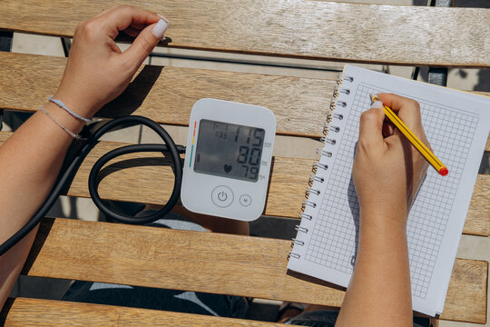 Woman Checking Blood Pressure With Digital Monitor At Home On Wooden Table, Health Check
