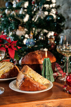 Festive Christmas Table With Sliced Panettone, Candle, Wine Glasses and Decorated Tree