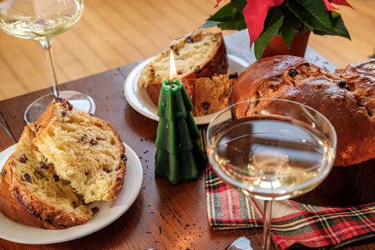 Festive Christmas Table With Sliced Panettone, Candle, Wine Glasses and Decorated Tree
