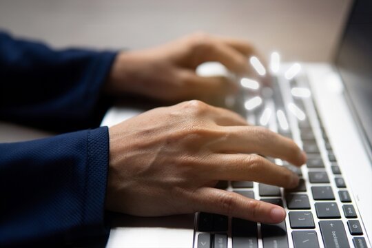 Hands typing on a laptop keyboard with a glowing digital sparkle. AI writing, smart integration, content generation, and digital workflow automation concept.