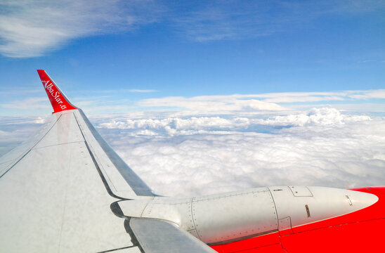 Aerial travel photography displaying cruising altitude clouds and aircraft structures under bright daylight.