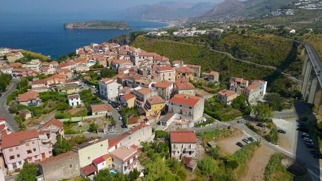 San Nicola Arcella one of the most beautiful villages of Italy, cinematic drone flyby over viaduct and pink rooftops to cliffside town, Dino island, Calabria, Italy. 4K establishing B-roll