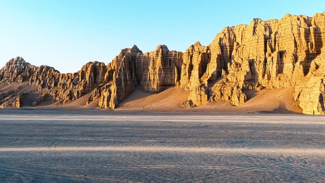 Golden sunlight illuminates towering yardang rock formations in Dahaidao desert, Xinjiang, creating stark dramatic shadows.
