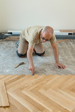 Herringbone oak parquet installation with carpenter marking the floor layout by hand.