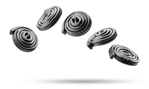 Liquorice candy wheels flying, isolated on white background.