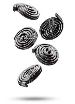 Liquorice candy wheels flying, isolated on white background.