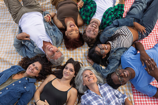 Overhead view of diverse friends lying in a circle on picnic blankets