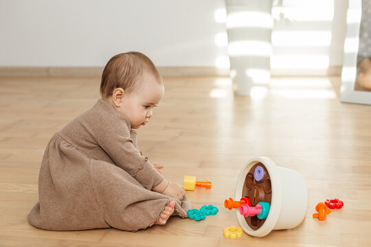 Baby sitting on floor exploring colorful shape sorter toy