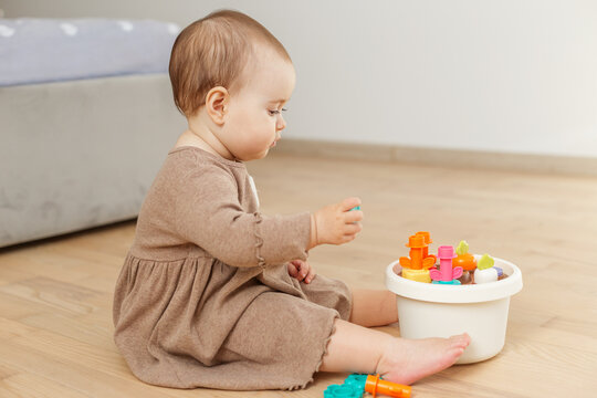 Baby holding toy shape sorter piece on floor
