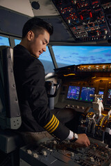 Young airline pilot operating controls in aircraft cockpit © LeNgoc