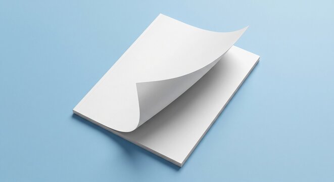 High-angle view of a blank white matte magazine mockup with a curled cover on a light blue background, showcasing soft shadows and clean paper texture.