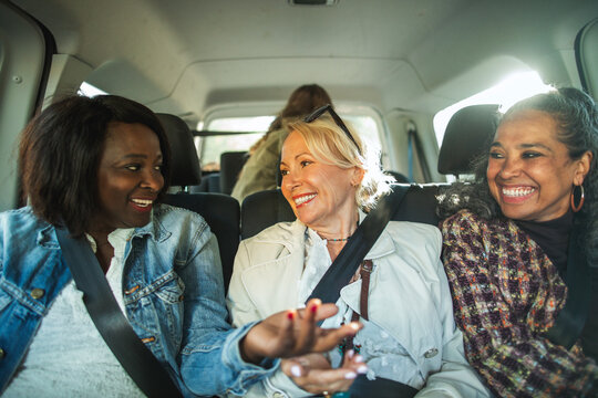 Smiling female friends talking with each other while traveling in car