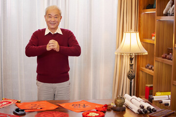 Happy elderly Asian man giving Lunar New Year greetings at home © LeNgoc