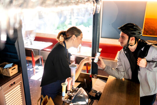 High angle view of delivery man showing order details on smart phone to restaurant owner