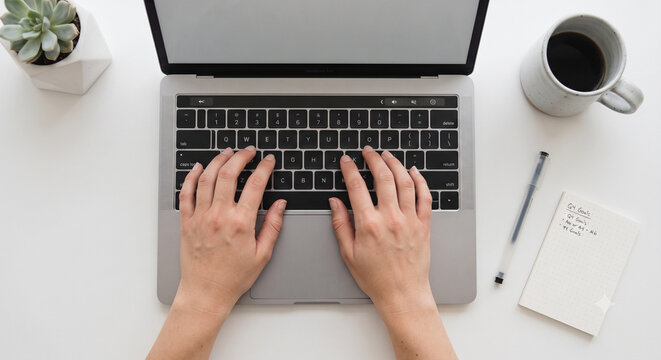 Top view of person hands typing on laptop keyboard on white office desk with coffee and notebook	커피와 노트북이 있는 흰색 사무실 책상 위에서 노트북 키보드를 타이핑하는 사람의 손 탑뷰