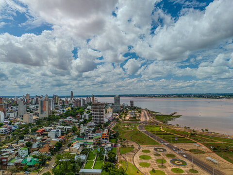 Aerial view of the Posadas skyline, featuring high-rise buildings and a riverfront park along the Parana River under a cloudy sky in Posadas, Misiones Province, Argentina.