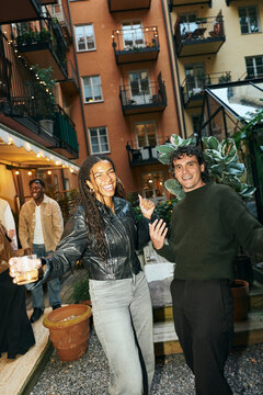 Portrait of young male and female friend dancing with each other at courtyard party